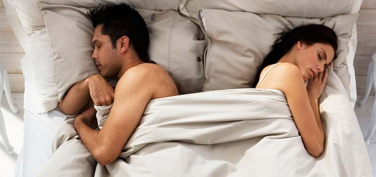 Couple in bed turned away from each other, illustrating when to go to therapy